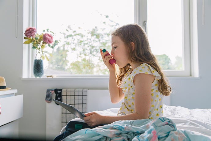 Young girl in exam room using an inhaler